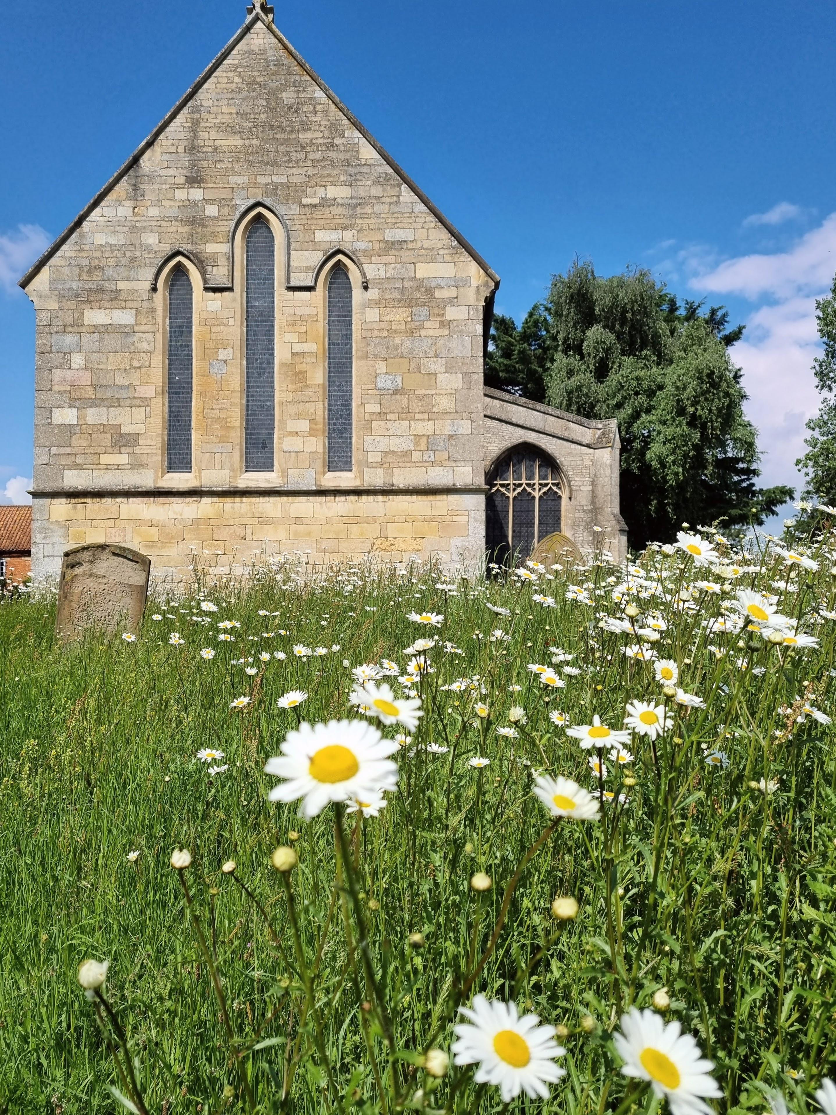 a photo of flowers in the graveyard of all saints church in ruskington
