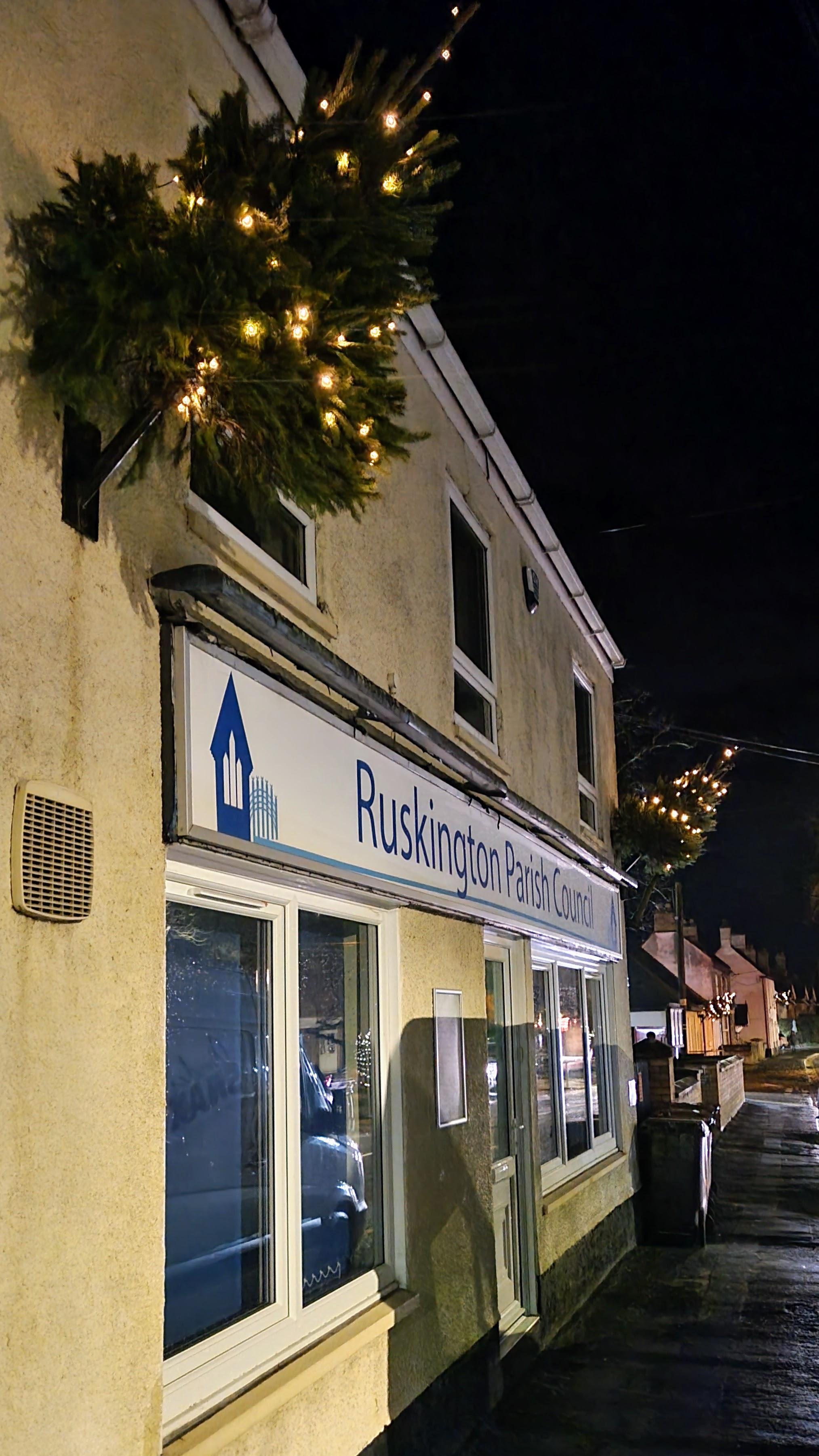 A festive street scene featuring a Christmas tree prominently displayed in front of a charming building.