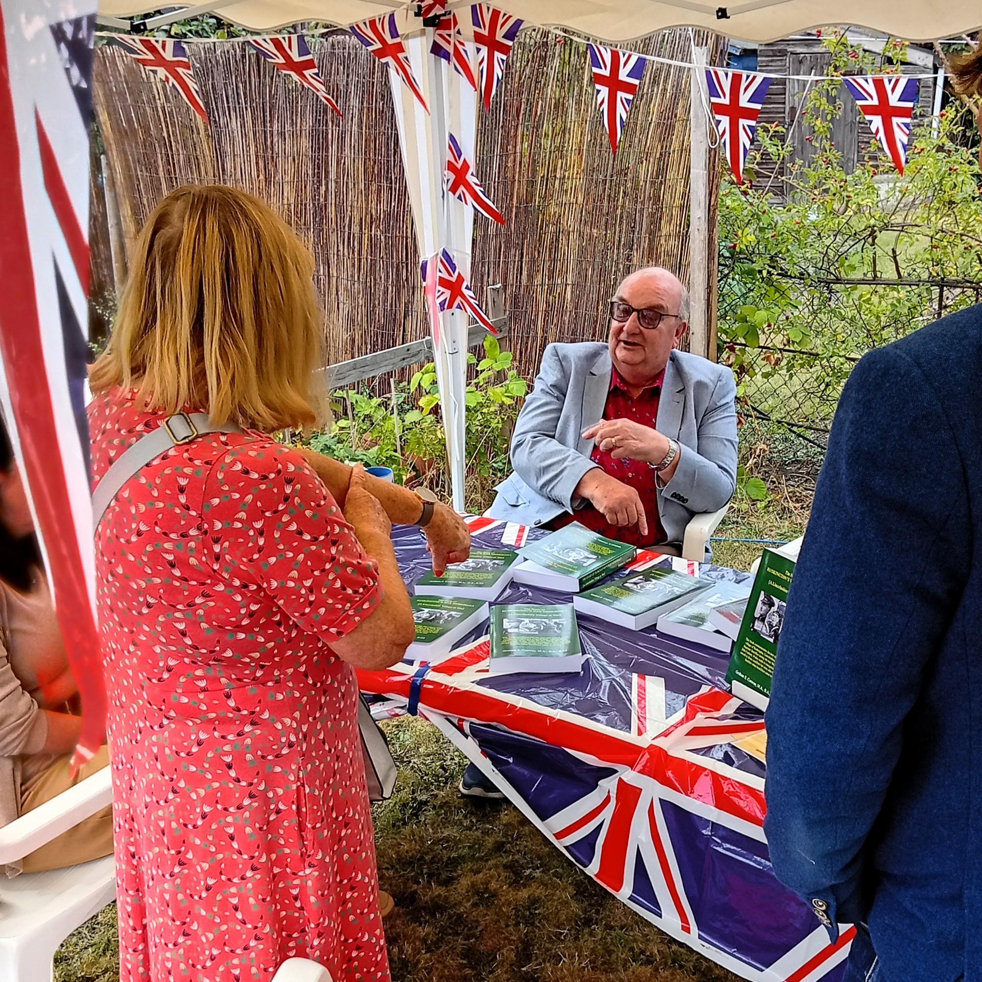 A man and woman stand under a colorful tent adorned with flags, smiling and enjoying the festive atmosphere.