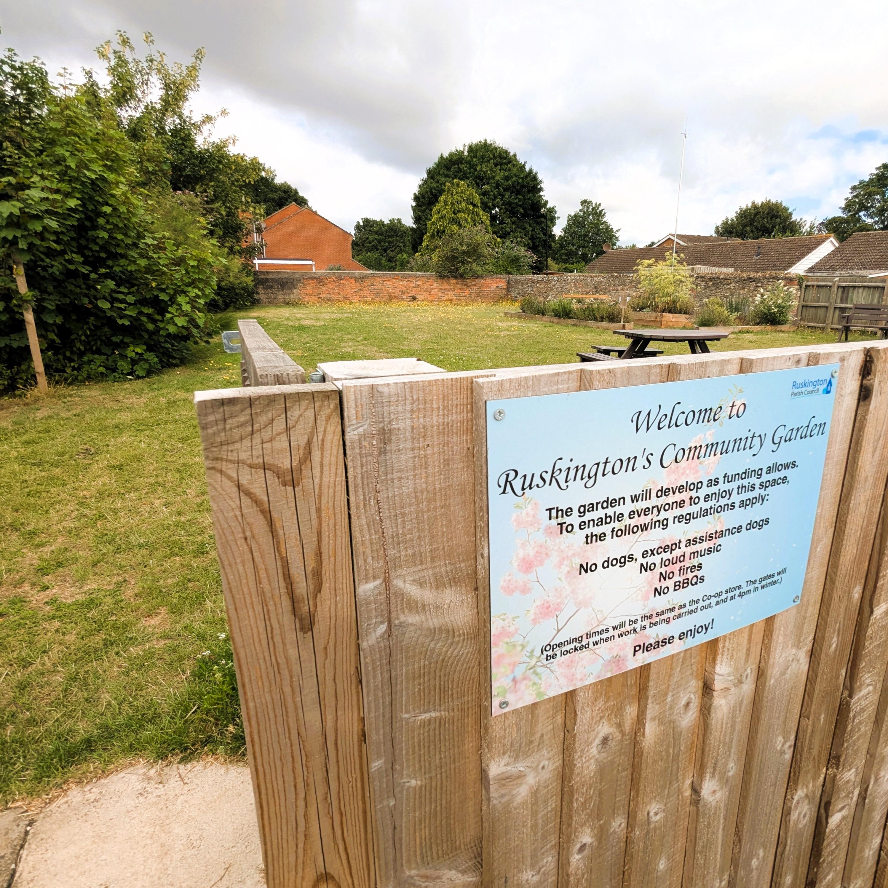 A wooden fence sign in a yard, displaying a message or information for visitors.