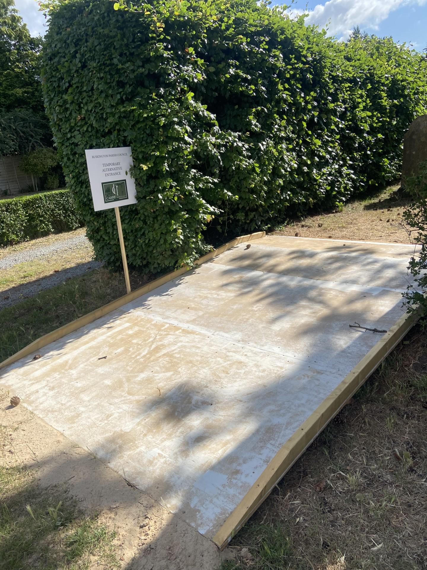 A construction site in a park featuring a concrete ramp under construction for improved accessibility.