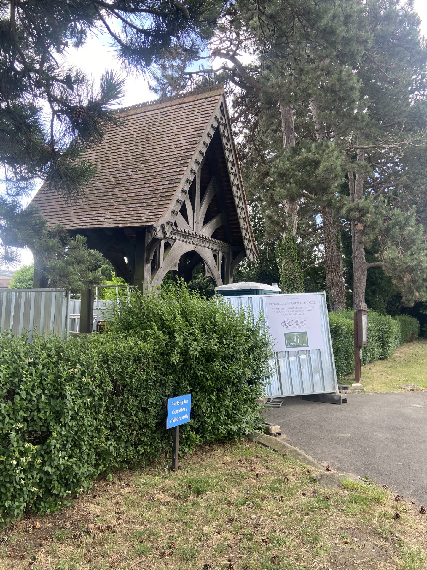 A quaint wooden structure with a visible sign, surrounded by greenery.