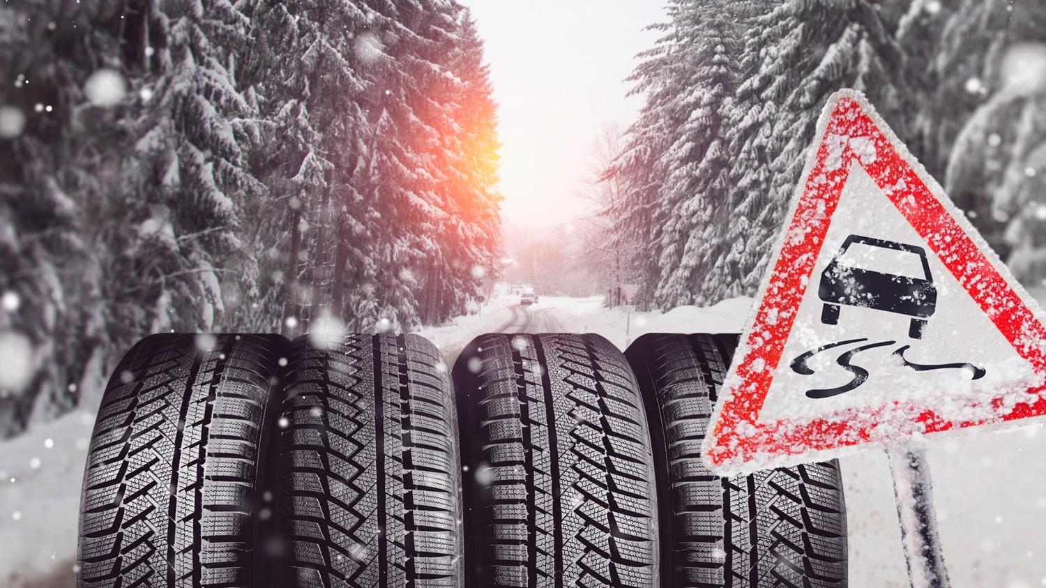 Winter tires displayed alongside a snow warning sign, emphasizing safe driving conditions in snowy weather.